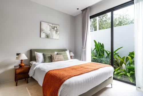 a bedroom with a bed and a large window at Botanica Zen by Villacarte in Ban Phru Champa