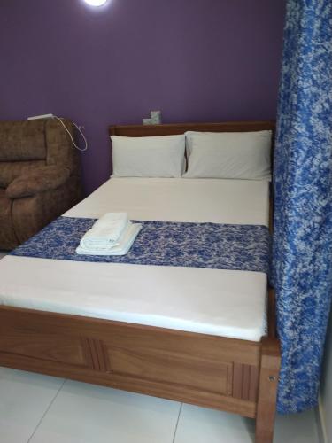 a bed with a wooden frame with a towel on it at Cossy Homes in Mtwapa