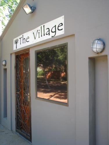 un edificio blanco con un cartel que lee el pueblo en The Village in Hatfield, en Pretoria