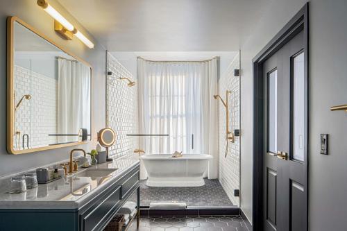 a bathroom with a tub and a large mirror at The Eliza Jane, Autograph Collection in New Orleans