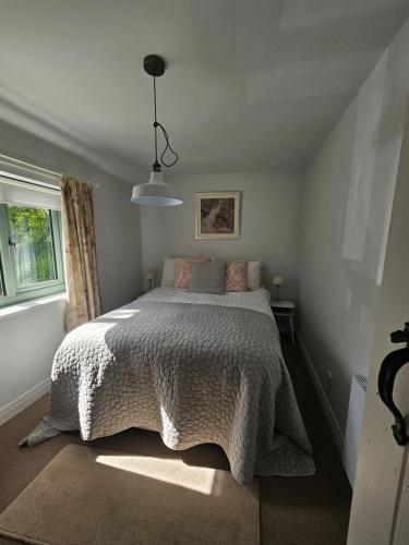 a bedroom with a bed with a white comforter and a window at Yederick Barn in Sawdon