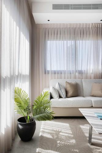 a living room with a couch and a plant at 2BR Balcony High Floor - Dizengoff Square View - MAMAD D80 in Tel Aviv