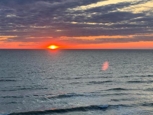 a sunset over the ocean with the sun setting at ''Jūras Mala'' in Labrags