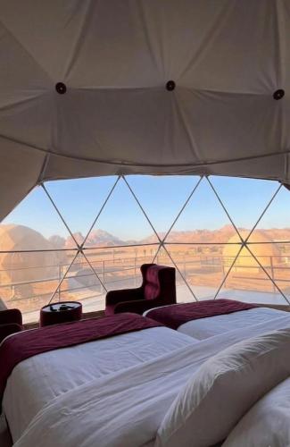 two beds in a tent with a view of the desert at WADI RUM NASA lUXURY BUBBLE in Wadi Rum
