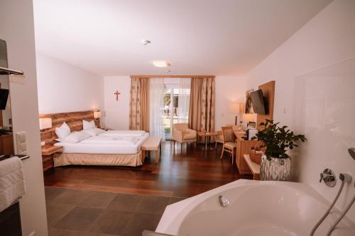 a bathroom with a bed and a living room with a tub at Relax- & Wanderhotel Poppengut in Hinterstoder