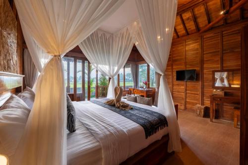 a bedroom with a bed with drapes at Uma Sunset Villa in Ubud