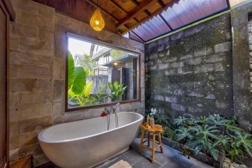 a bath tub in a bathroom with plants at Uma Sunset Villa in Ubud