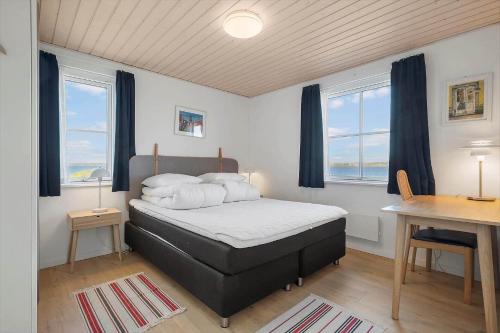 a bedroom with a bed and a desk and windows at LF15113-Farso-Strandvejen-12-B in Farsø