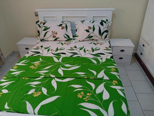 a bed with a green and white comforter and pillows at Amidez Apparts in Zalom