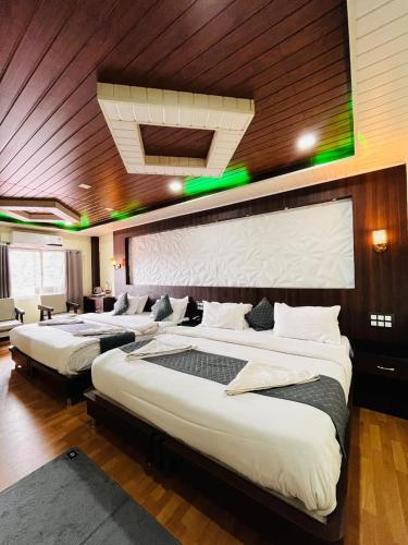 a hotel room with three beds in a room at Hotel La Gowri, Coorg in Madikeri
