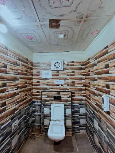 a bathroom with a toilet and a wooden wall at Hotel La Gowri, Coorg in Madikeri