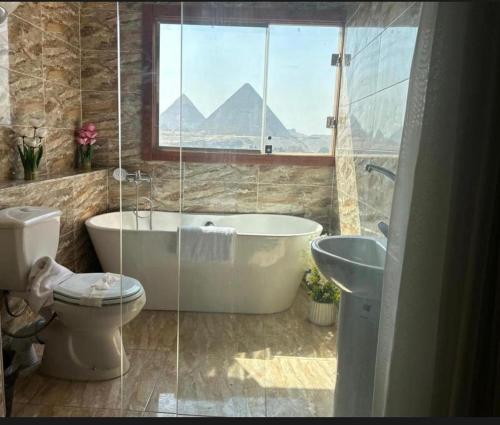 a bathroom with a tub and a toilet and a sink at Vida Pyramids Inn in Cairo