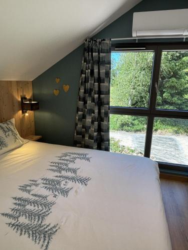 a bedroom with a bed and a large window at Le Petit Nid Gerardmer in Gérardmer