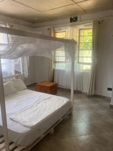a bedroom with a white bed and two windows at Kilifi Hideaway,Spacious Coastal Retreat in Kilifi