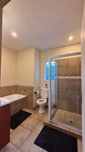 a bathroom with a tub and a toilet and a shower at Success Guesthouse in Nelspruit