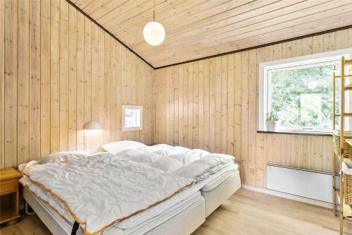 a bedroom with a white bed in a wooden wall at LF483-Snedsted-Bjergvej-8 in Snedsted
