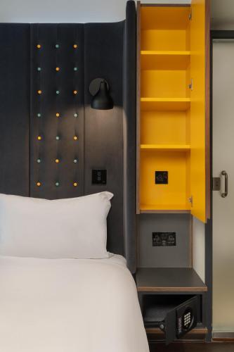 a bedroom with a bed and a yellow cabinet at Point A Hotel Edinburgh St Andrew Square in Edinburgh