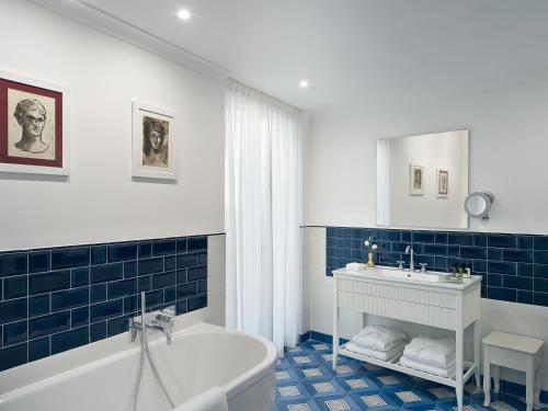 a bathroom with blue tiles and a tub and a sink at Il Tipografo di Amalfi A Family Museum Hotel in Amalfi