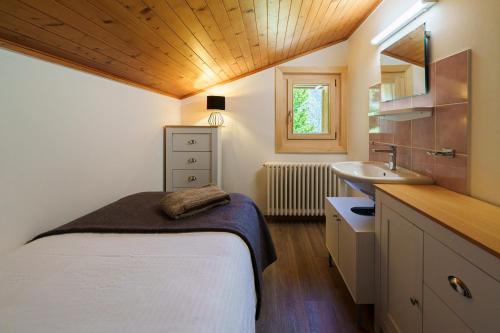 a small bedroom with a bed and a sink at Chalet des Cheneaux in Bruson