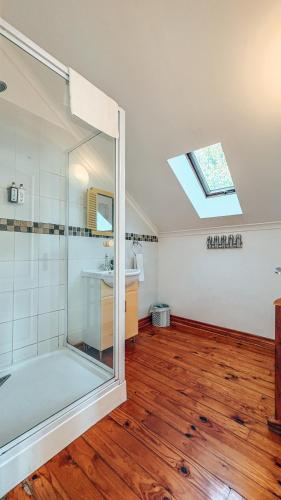 a bathroom with a shower and a sink and a skylight at Buff and Fellow by the Bay in Great Brak River