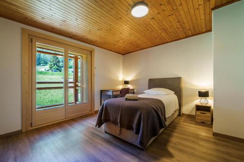 a bedroom with a bed and a large window at Chalet des Cheneaux in Bruson