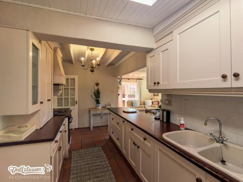 a kitchen with white cabinets and a sink at Critchley Common in Dullstroom
