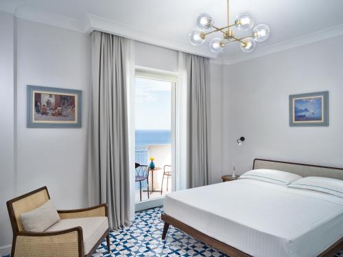 a bedroom with a bed and a chair and a window at Il Tipografo di Amalfi A Family Museum Hotel in Amalfi