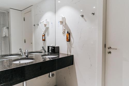 a bathroom with three sinks and a mirror at Hotel Porto Downtown in Porto