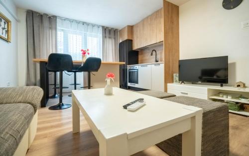 a living room with a white coffee table and a kitchen at Apartman Lili in Knin