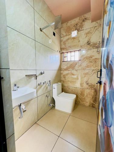 a bathroom with a toilet and a sink and a shower at Breeza Residency in Kazhakuttam