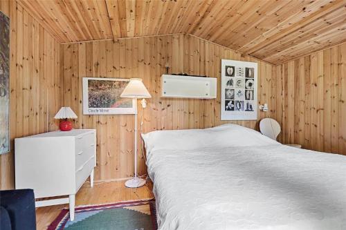 a bedroom with a white bed in a wooden wall at 10054-Rorvig-Lindegardsvaenget-27 in Rørvig
