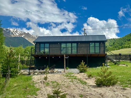 a house in a field with mountains in the background at Uno Cottage Kazbegi in Kazbegi