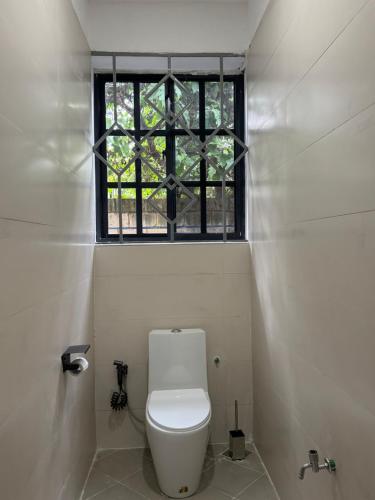 a white toilet in a bathroom with a window at Kili Maisha Grand Home in Moshi