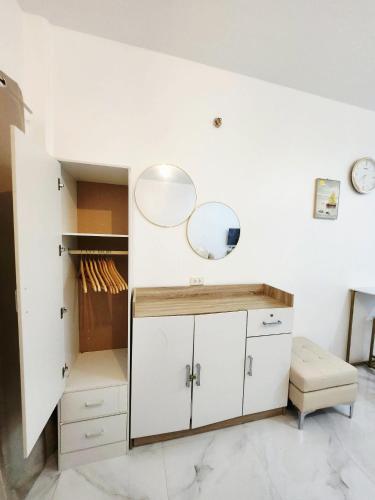 a bathroom with white cabinets and two mirrors at AJB Royal Ocean Crest Mactan Cebu in Cebu City
