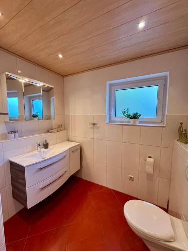 a bathroom with a sink and a toilet and a window at Ferienwohnung Sattler in Mistelgau