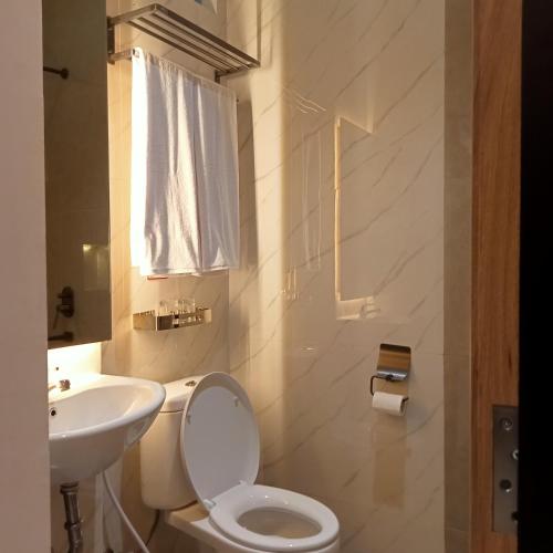 a white bathroom with a toilet and a sink at NH Residence Yogyakarta in Ngabean