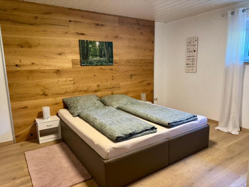 a bed in a room with a wooden wall at Ferienwohnung Sattler in Mistelgau
