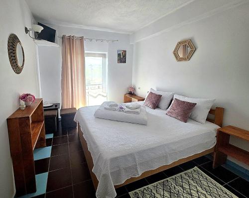 a bedroom with a bed with white sheets and pink pillows at Pensiunea Mallorca Restaurant - Bar in Vişeu de Sus