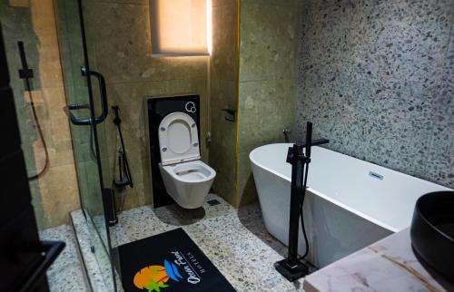 a bathroom with a toilet and a bath tub at Ocean Front Hotels Enugu in Awkuzu