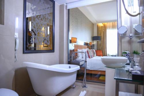 a bathroom with a tub and a sink and a bed at Balaji Sarovar Premiere in Solapur