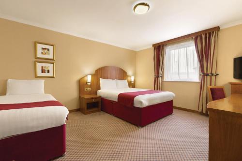 
a hotel room with two beds and two lamps at Savera Hotel South Ruislip in Hillingdon
