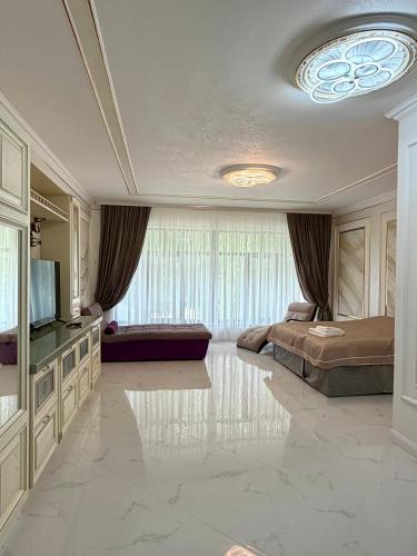 a large living room with a bed and a television at Mirali Resort in Almaty