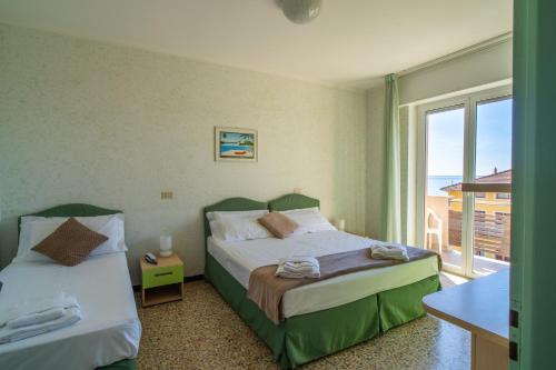 a bedroom with two beds and a balcony at Hotel Corallo in Pietra Ligure