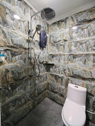 a stone bathroom with a toilet and a shower at PULANG RESORT in Setiu