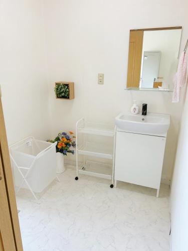 a white bathroom with a sink and a mirror at 田園の宿 in Takehanachō