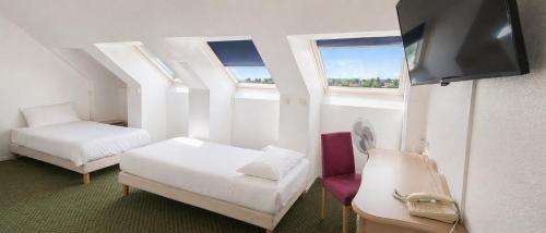 a room with two beds and a flat screen tv at Hôtel Ikar Blois Sud in Saint-Gervais-la-Forêt