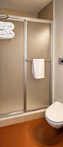 a bathroom with a shower with a toilet and a towel at Hôtel Ikar Blois Sud in Saint-Gervais-la-Forêt