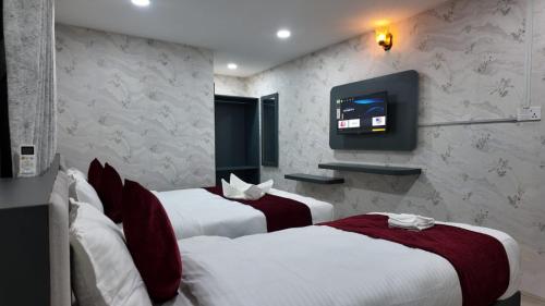 a hotel room with three beds and a flat screen tv at Bhandari hotel and sekuwa corner in Pashupatināth