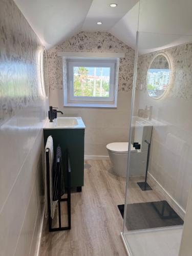 a bathroom with a sink and a toilet and a window at Vila Sotto Mayor in Figueira da Foz