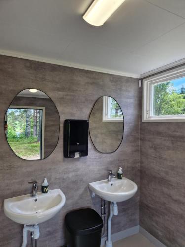 a bathroom with two sinks and two mirrors at Långseruds Stugby Nature Cabins in Byn